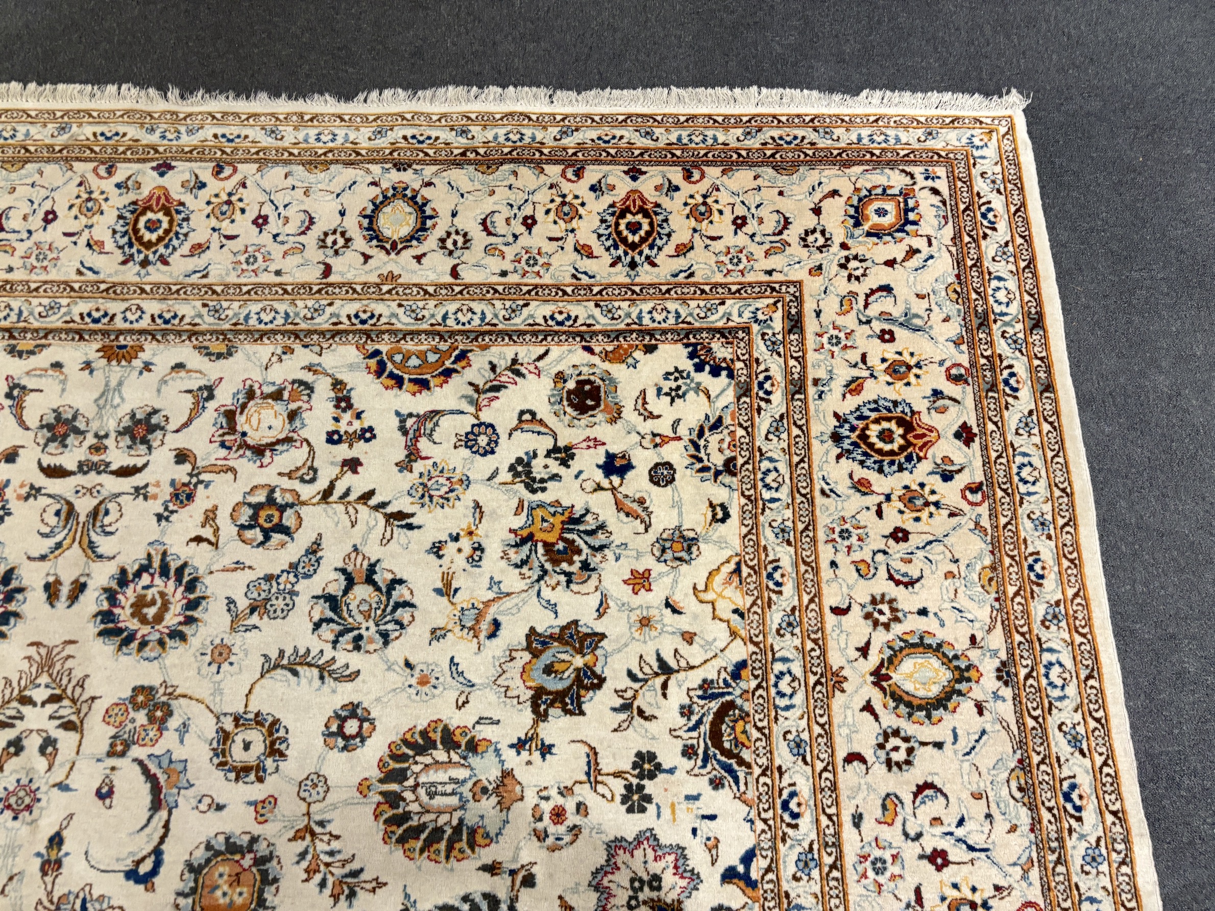 A Kashan ivory ground carpet, central field of foliate motifs, multi bordered, 400 x 308cm, Please note this lot attracts an additional import tax of 5% on the hammer price